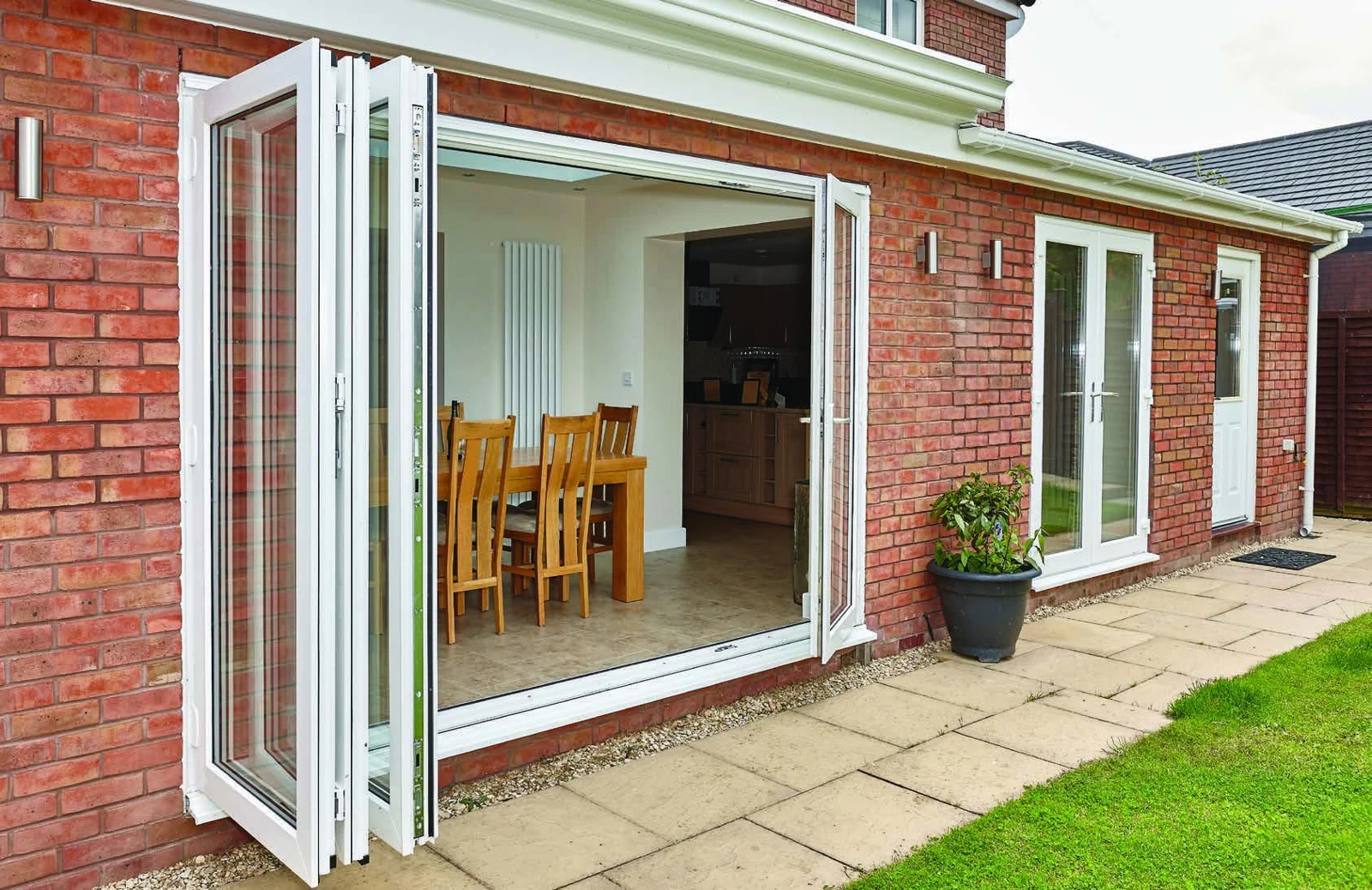 White REHAU PVCu bi-fold doors folded open onto a patio